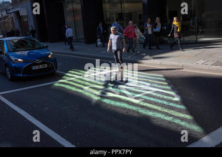 In einem Bereich des reflektierten Lichts, ein Mann kreuze Threadneedle Street vor stoppte der Verkehr in der Londoner City - die Capital Financial Center (aka der Square Mile), am 27. September 2018 in London, England. Stockfoto
