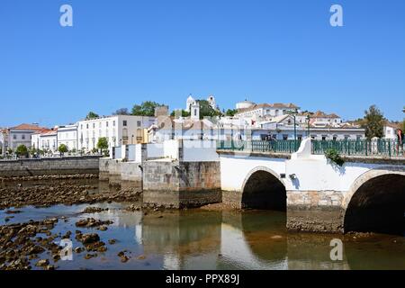 Blick auf die römische Brücke (Ponte Romano) und den Fluss Gilao mit Stadt Gebäude an der Rückseite, Tavira, Algarve, Portugal, Europa. Stockfoto