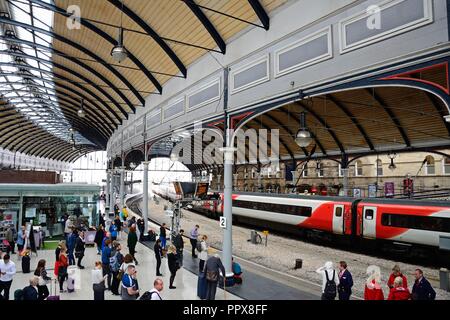 Passagiere warten am Bahnsteig in der Newcastle Hauptbahnhof mit Geschäften und Cafés an der Rückseite, Newcastle upon Tyne, Tyne und Wir Stockfoto