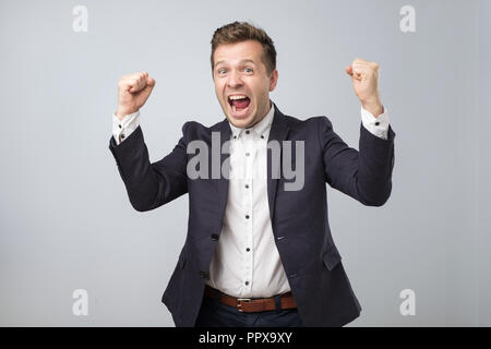 Porträt einer sehr glücklich business Mann stand auf grauem Hintergrund Stockfoto