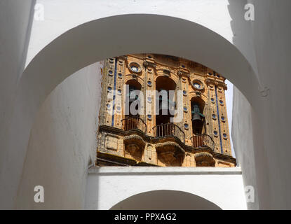 Bögen und weiß getünchte Wand Framing der Glockenturm der Kirche Santa Maria Mayor im historischen Zentrum von Arcos de la Frontera, Andalusien, Spanien. Stockfoto