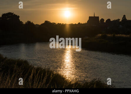Blick auf den Sonnenuntergang über dem Fluss Arun und Arundel im Sommer in West Sussex, England, UK. Sonne über Wasser mit Reflexion. Stockfoto