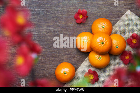 Das chinesische Neujahr - Mandarin Orangen auf Holztisch mit Blume im Vordergrund Stockfoto