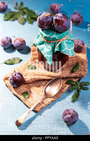 Süße Pflaumen marmelade im Glas auf Blau alte Tabelle Stockfoto