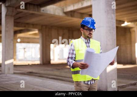 Techniker arbeiten auf der Baustelle und Holding Blueprint Stockfoto