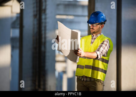 Techniker arbeiten auf der Baustelle und Holding Blueprint Stockfoto