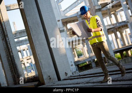 Techniker arbeiten auf der Baustelle und Holding Blueprint Stockfoto