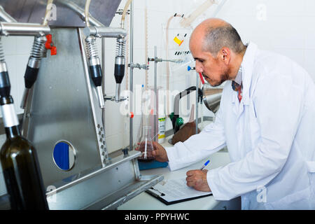 Professionelle man Arbeiten mit Qualität Tests in Wein Manufaktur Labor Stockfoto