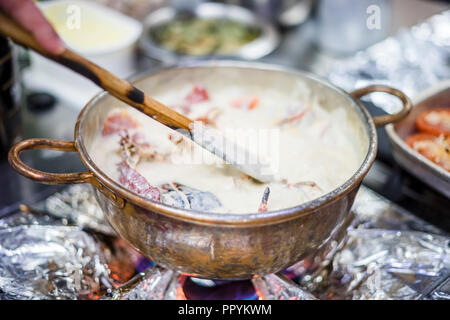 Hummersuppe auf Basis von Milch und Rotwein in Kupfer Topf zubereitet Stockfoto