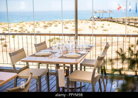 Tabelle mit Teller, Gläser und Besteck bereit für ein Mittagessen in einem Restaurant mit Meerblick Stockfoto