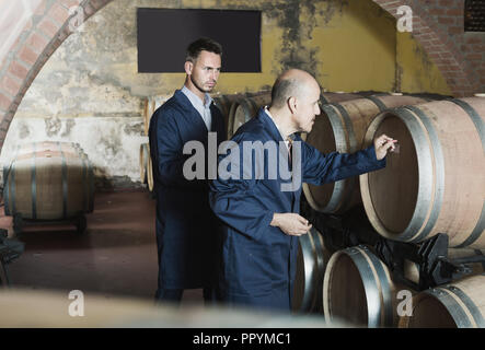 Porträt von zwei männlichen Weingut Mitarbeiter tragen Mänteln im Weingut Keller arbeiten. Selektiver Fokus Stockfoto