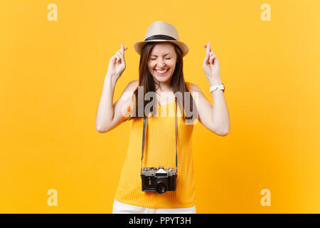 Touristische Frau im Sommer legere Kleidung hat halten die Finger gekreuzt, die Augen geschlossen auf gelbem Hintergrund. Weibliche Passagier ins Ausland reisen zu Trave Stockfoto