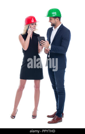 Junge Ingenieur Frau und Frau in Helm Kommunikation über mobile Geräte, isoliert auf weißem Stockfoto