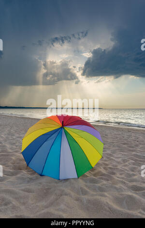 Bunte Sonnenschirme am Strand gegen die drastischen stürmischen Wolken Stockfoto