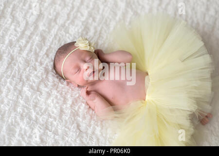 Schlafen, neugeborene Mädchen tragen eine gelbe Blume Kopfbügel und Tutu. Stockfoto