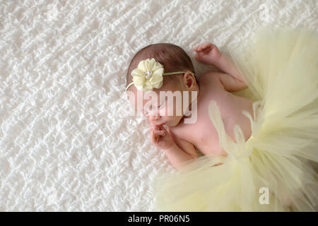 Eine Warnung, 2 Woche alt neugeborenes Mädchen tragen eine gelbe Blume Kopfbügel und Tutu. Stockfoto