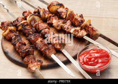 Gegrilltes Schwein am Spieß gebraten auf den Grill auf Holz Schneidebrett mit Tomatensauce in eine Schüssel geben. Grill, Picknick Stockfoto