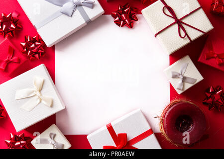 Weiß und Rot Geschenk auf rotem Hintergrund mit Papier Karte für Text. Weihnachten Konzept. Stockfoto