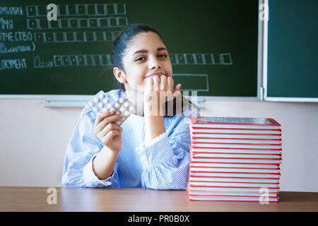 Smiling Student mit piils sitzt in der Nähe der Tafel im Klassenzimmer Stockfoto