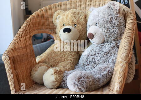 Zwei Teddybären zusammen sitzen auf einem korbstuhl Stockfoto