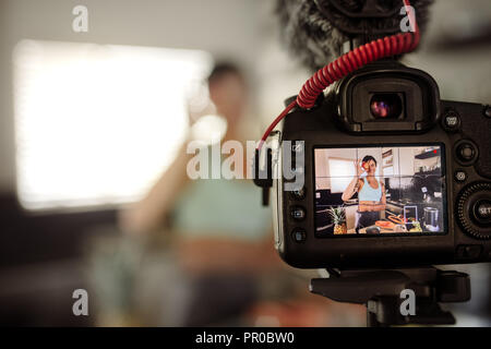 Kamera Bildschirm mit Frau mit einem Früchte vor Ihren Augen in der Küche. Frau, die ein Video für Ihren Blog über gesundes Essen. Stockfoto