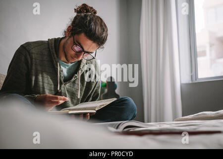 Student studieren für Prüfungen, zu Hause zu sitzen. Junger Mann, Bücher zu lesen, mit Konzentration der Vorbereitung auf Prüfungen. Stockfoto