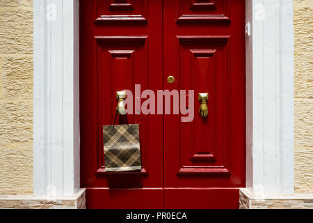 Tasche hängt an Türknopf in Form einer Hand, in Malta. Stockfoto