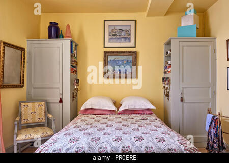 Gerahmte Kunstwerke von deliss Familie über Doppelbett mit Einbauschränken Stockfoto