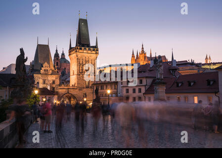 Charles Brücke, Türme, und die Prager Burg bei Nacht mit unscharfen Fußgänger, UNESCO-Weltkulturerbe, Prag, Tschechische Republik, Europa Stockfoto