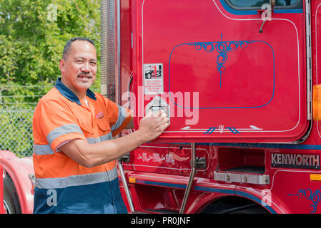 Ein glückliches Samoan LKW-Fahrer in Hi-vis Kleidung, Klettern in der Kabine des roten Auflieger Prime Mover Lkw Stockfoto
