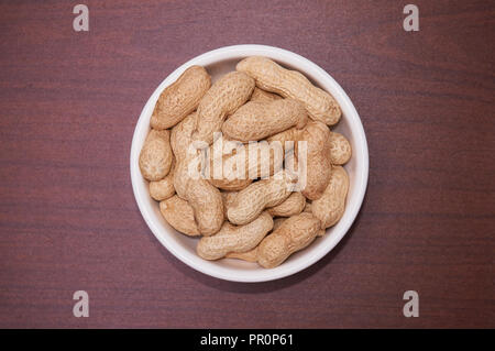 Erdnüsse ungereinigte vor dem Hintergrund der braun Holz. Stockfoto