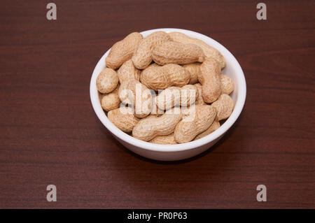 Erdnüsse ungereinigte vor dem Hintergrund der braun Holz. Stockfoto