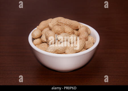 Erdnüsse ungereinigte vor dem Hintergrund der braun Holz. Stockfoto