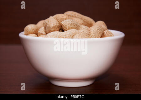 Erdnüsse ungereinigte vor dem Hintergrund der braun Holz. Stockfoto