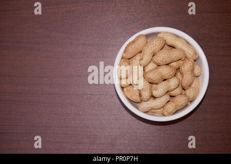 Erdnüsse ungereinigte vor dem Hintergrund der braun Holz. Stockfoto