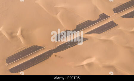 Luftaufnahme von einer Wüste Straße von Sanddünen, fotografiert von einer Drohne bei Sonnenaufgang. Dubai, VAE. Stockfoto