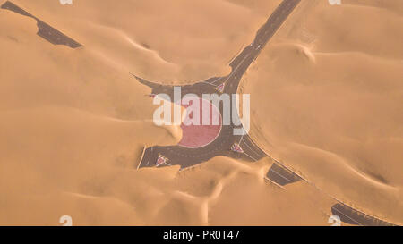 Luftaufnahme von einer Wüste Straße von Sanddünen, fotografiert von einer Drohne bei Sonnenaufgang. Dubai, VAE. Stockfoto