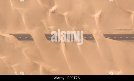 Luftaufnahme von einer Wüste Straße von Sanddünen, fotografiert von einer Drohne bei Sonnenaufgang. Dubai, VAE. Stockfoto