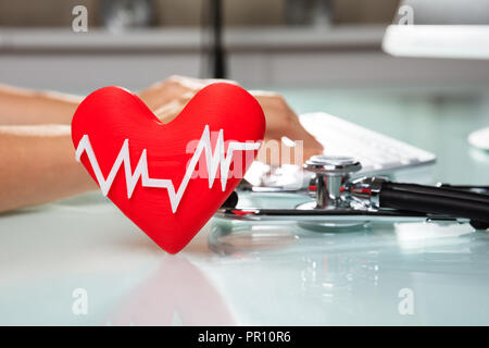Rotes Herz mit Heartbeat Puls Vor der Arzt Arbeiten am Computer Stockfoto