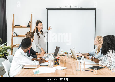 Jungen asiatischen Geschäftsfrau auf Leinwand während der Präsentation im Büro Stockfoto