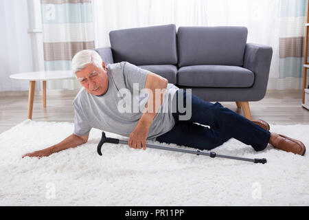 Älterer Mann gefallen Auf dem Teppich mit Stock Stockfoto