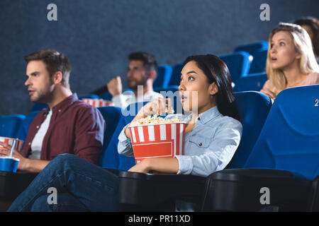 Asiatische Frau mit Popcorn anschauen Film im Kino allein schockiert Stockfoto