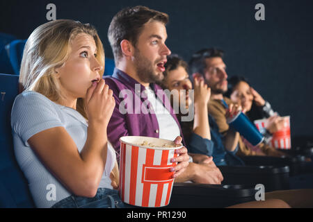 Erschrocken multiethnischen Freunde mit Popcorn anschauen Film zusammen im Kino Stockfoto
