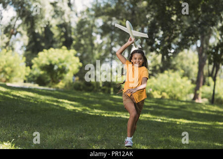 Nettes glückliches Kind werfen Flugzeug in Park Stockfoto