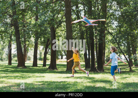 Cute glückliche Kinder spielen mit bunten Drachen in Park Stockfoto