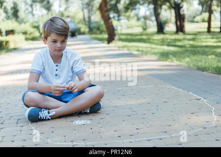 Cute little boy Zeichnen mit Kreide in Park Stockfoto