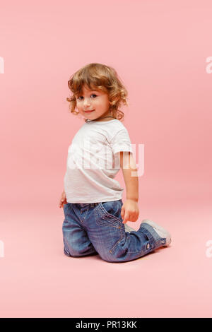 Portrait von Glückliche freudige schöne kleine Junge, studio Schuß auf Rosa Stockfoto