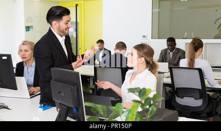 Gut aussehender bärtiger Mann reden und flirten mit attraktiven lächelnde Frau, die in co-Arbeitsbereich Stockfoto