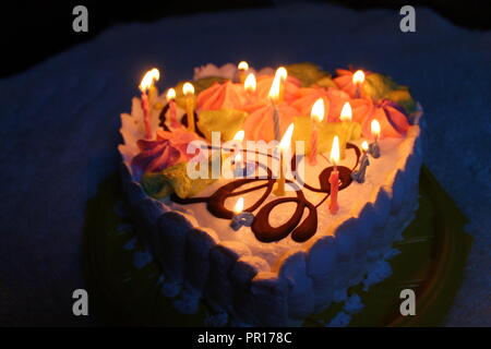 Luftig Sahnetorte in der Form des Herzens mit Kerzen für Geburtstag Stockfoto