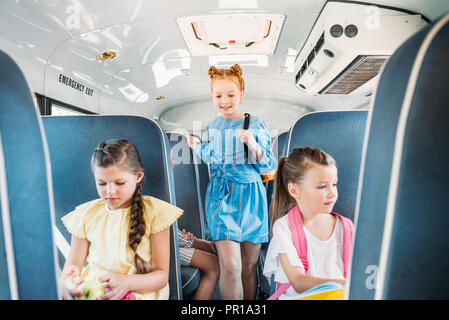 Adorable kleine Schüler reiten auf Schulbus während der exkursion Stockfoto